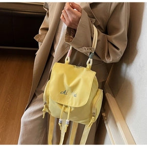 Detail des gelben Nylon-Rucksacks mit geflochtenem Seilgriff und blauer Ai Mei Stickerei