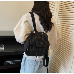 Detail eines Nylon-Rucksacks mit Kordelzugverschluss und bunten Perlen-Dekorationen