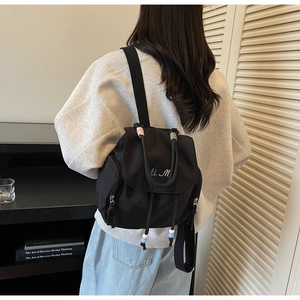 Detailansicht eines schwarzen Nylon-Rucksacks mit blau-weißer ti M Stickerei