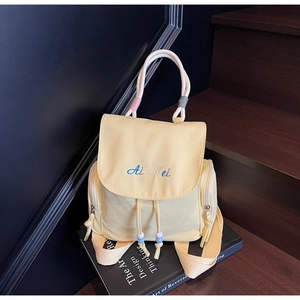 Detail eines hellgelben Nylon-Rucksacks mit Stickerei und bunten Seil-Tragegriffen