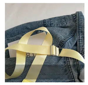 Detail of a bright yellow woven nylon strap with a silver adjustable metal buckle on a bag