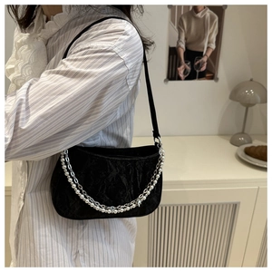 Detail of black velvet shoulder bag with layered pearl and silver chain straps
