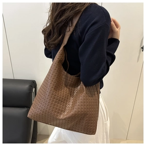 Close-up of caramel brown woven leather tote bag showing intricate craft and texture
