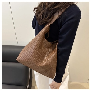 Close-up of the woven texture and soft leather silhouette on a brown tote shoulder bag