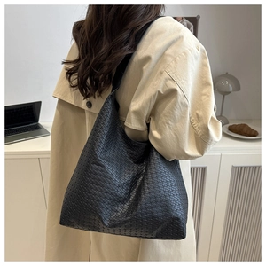 Detail of a black woven leather tote bag featuring a classic Intrecciato weave pattern