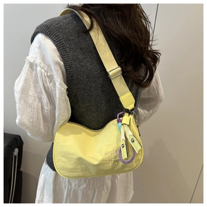 Detail view of yellow nylon crescent crossbody bag with white embroidery and wide strap