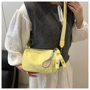 Detail of bright yellow nylon crossbody bag featuring embossed CHOU logo and braided charm