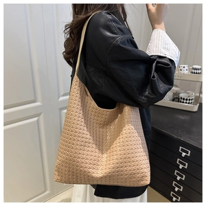 Détail du sac fourre-tout tressé abricot montrant la texture géométrique et la bandoulière