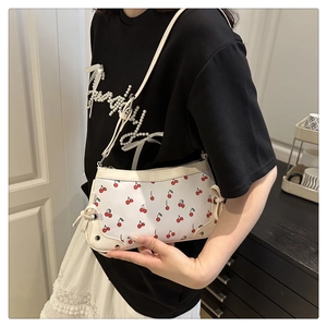 Detail of white PU leather shoulder bag with cherry print and side bow decoration