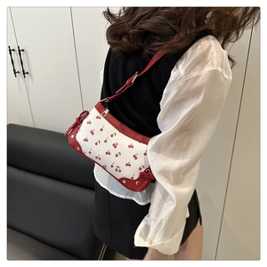 Detail showing vintage cherry print handbag with red leather trim and gold studs