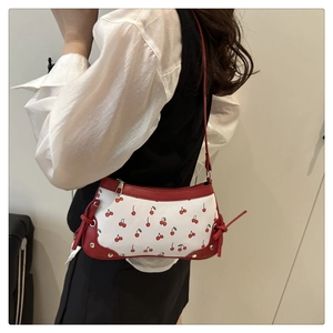 Detail of cute cherry print baguette bag with red strap and silver zipper closure