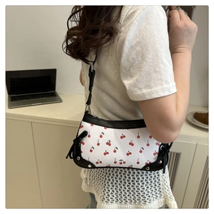 Close-up of white cherry print shoulder bag with black leather trim and silver studs