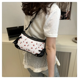 Detail of white baguette bag with cherry print and black leather bow with silver studs