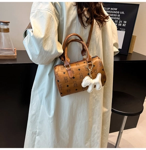 Détail d'un sac Boston marron avec imprimés ours et breloque chiot porté à l'épaule