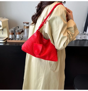 Detail of red woven hobo bag with knotted handle shown against a trench coat