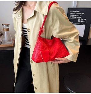 Détail du sac à bandoulière tressé rouge avec sangle en spirale et breloque assortie