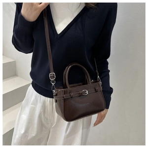 Close-up of a chocolate brown square crossbody bag styled with a blue knit sweater