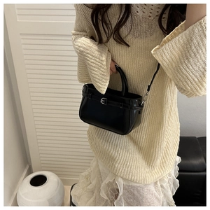 Detail of a chic black leather handbag featuring a decorative strap and silver metal buckle