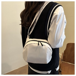 Rear view of model wearing a white canvas shell crossbody bag with adjustable strap