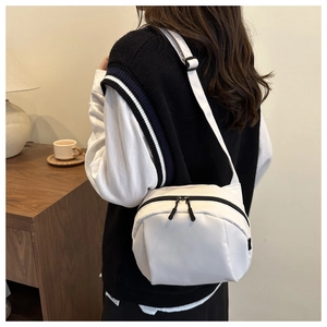 Detail of white canvas shell bag featuring smooth zippers and adjustable black straps