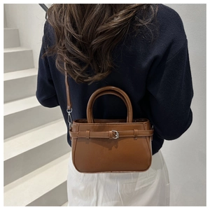 Detail view of a vintage brown crossbody bag with leather texture and metal buckle accents