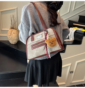 Detailed view of gray linen tote bag with brown faux leather trim and plush bear charm