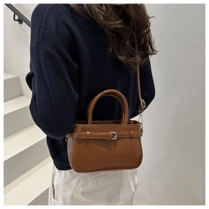 Rear view of a model wearing the dark brown PU leather handbag with shoulder strap