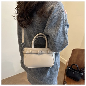 Detail of cream crossbody square bag with decorative buckle and slim shoulder strap