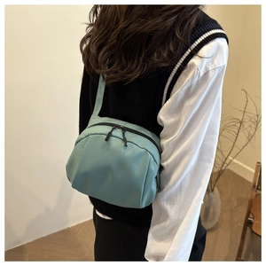 Detail view of light blue nylon shell bag with premium black double zippers and side label