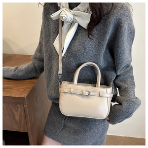 Chic beige mini leather handbag styled with a cross-body strap and elegant double handles