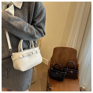 Close-up of minimalist crossbody square bag with double handles and adjustable strap
