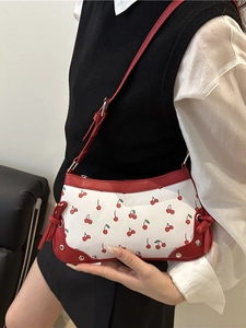 Retro shoulder bag with red cherry print and leather trim shown on female model