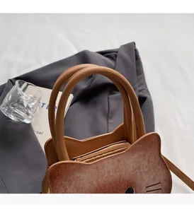 Macro detail of the brown cat-shaped handbag featuring durable leather handles and top zipper