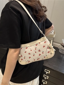 Chic white shoulder bag with cute red cherry prints and side bow details on a model