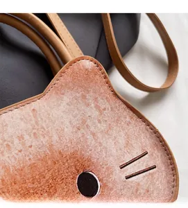 Detail of soft flocked fabric on a cat-shaped crossbody bag with embroidered whiskers