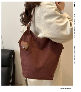 Detail of dark brown matte suede tote bag with leather piping and decorative charm