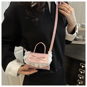 Detail view of mini pink crossbody bag with white lace trim and bow on the flap