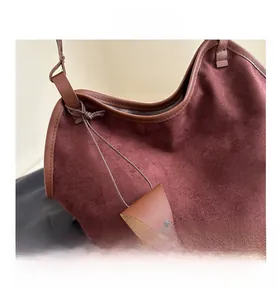 Close-up of burgundy suede tote bag showing leather edges and hanging charm detail