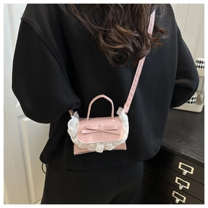Detail der rosa Mini-Umhängetasche mit weißer Spitze und Schleife, getragen am Model