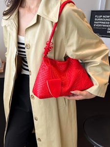 Sac à bandoulière chic en cuir tressé rouge avec poignée nouée porté par un mannequin