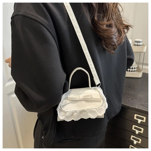 Detailansicht der weißen PU-Minibag mit dekorativer Schleife und feiner Spitze