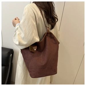 Deep brown suede shoulder bag with leather trim and metal buckles shown on a model