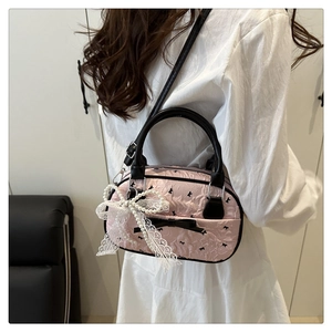 Close-up of pink ruffled bowling bag with lace bow, pearl chain and black leather straps