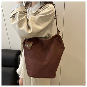 Detail of dark brown suede bucket bag featuring leather trim and a detachable coin pouch