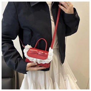 Detail of red mini crossbody bag with delicate bow and white lace trim decoration