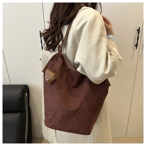 Gros plan sur le sac cabas en daim marron foncé avec mini pochette et lanière en cuir