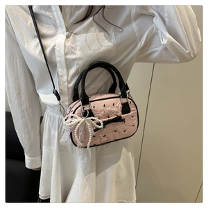 Détail d'un sac à main rose avec imprimé nœud noir et breloque en perles