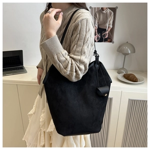 Detail of black suede bucket bag with gold clasp coin purse on minimalist interior background