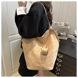 Detail of beige suede tote bag shown on shoulder highlighting its soft slouchy texture