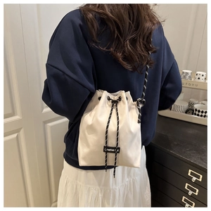 Detail of white canvas bucket bag with Creative Cat label and woven rope shoulder strap